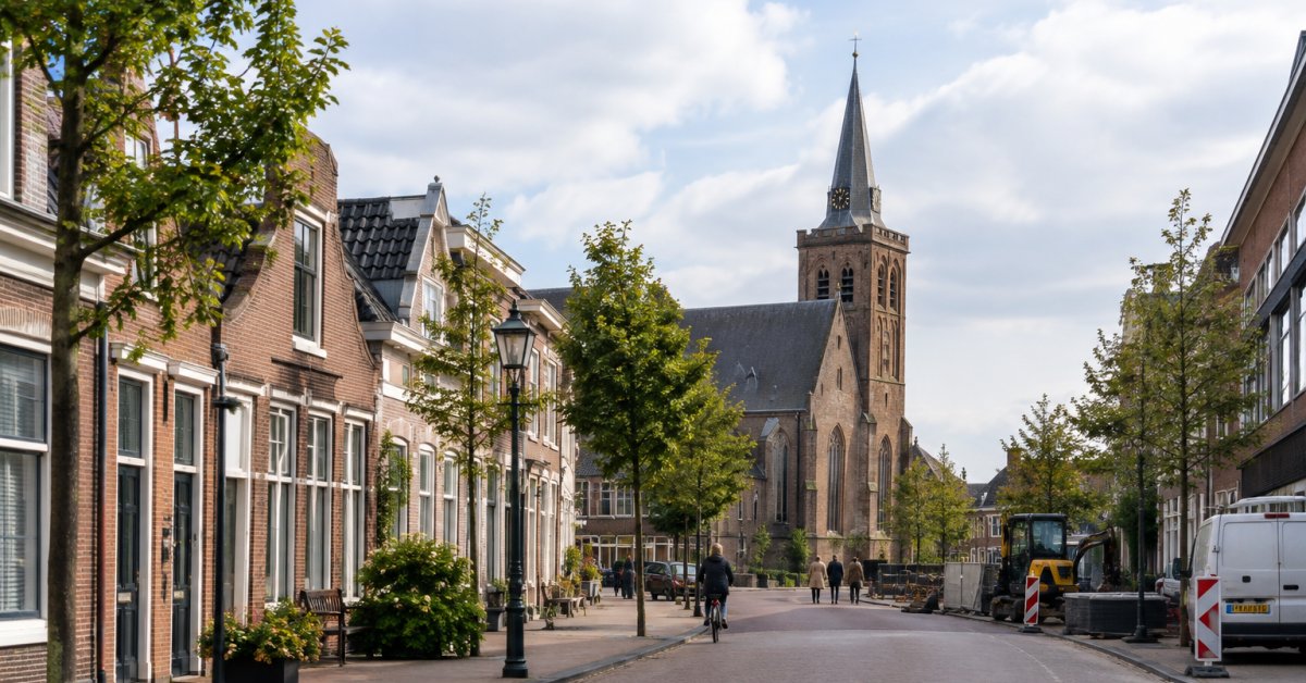 De Dorpsstraat met historische gevels en een kerktoren aan het einde van de straat.